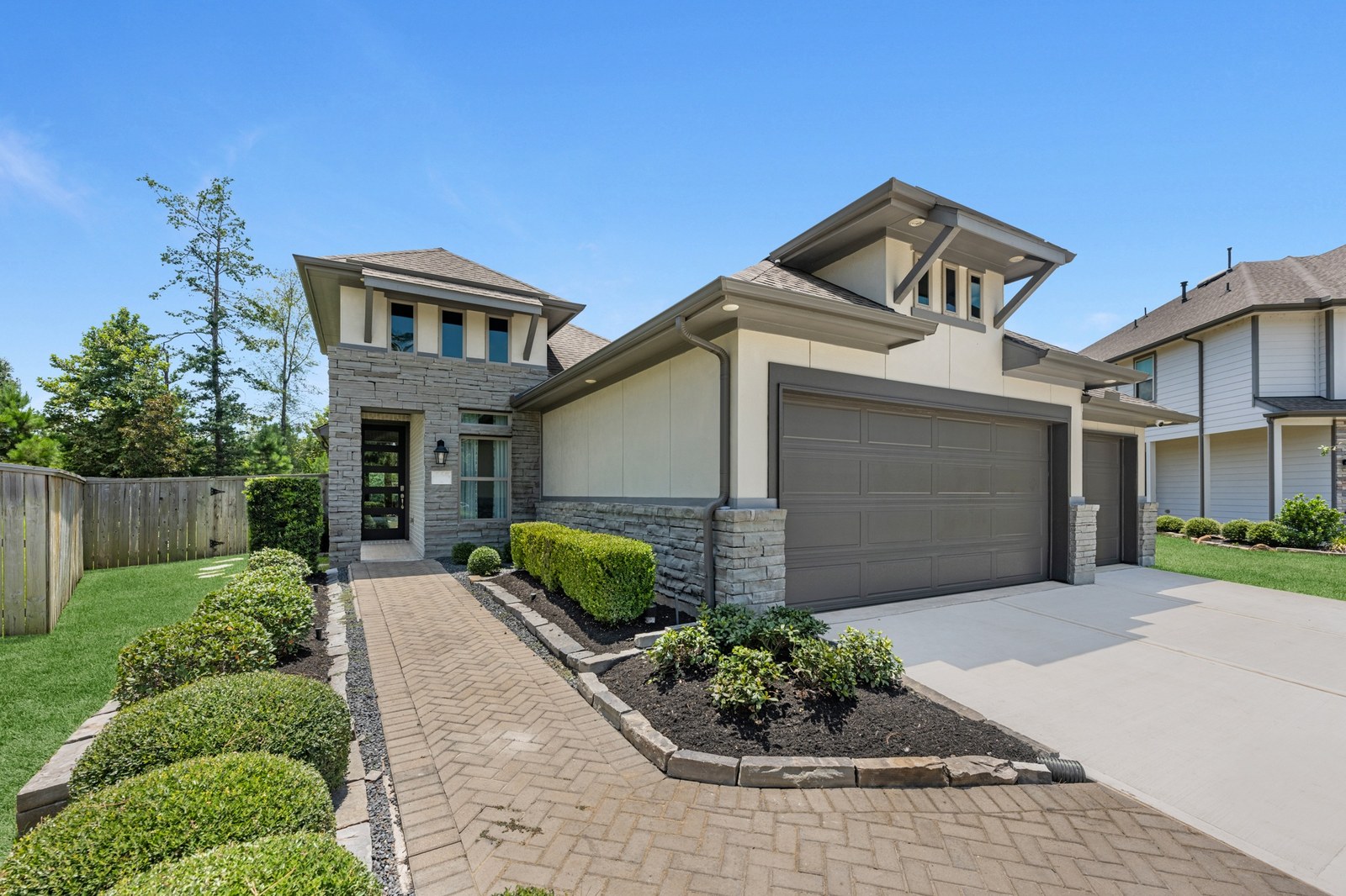 New-construction home with stone accents, a paver walkway and a two-car garage