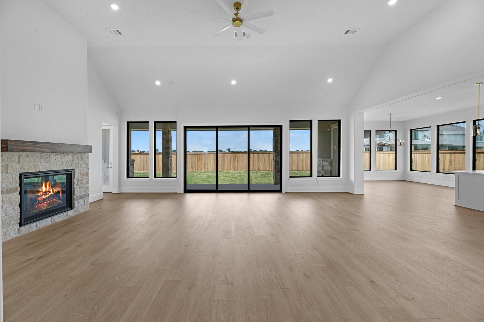 Bright open-concept new-construction living area with a fireplace and wide windows