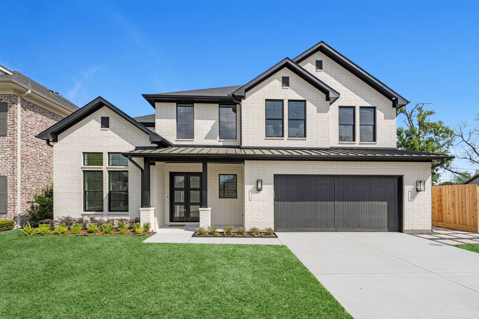 White brick two-story new-construction home with black trim and a two-car garage