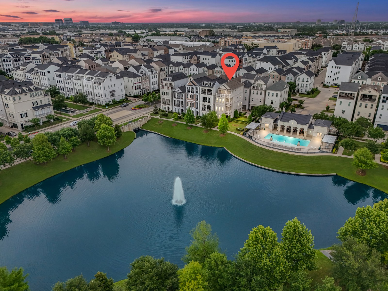 Aerial of a lakeside neighborhood at dusk with a location pin
