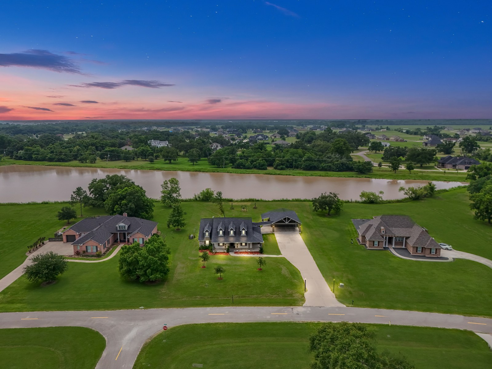 Aerial of acreage homes beside a river at dusk