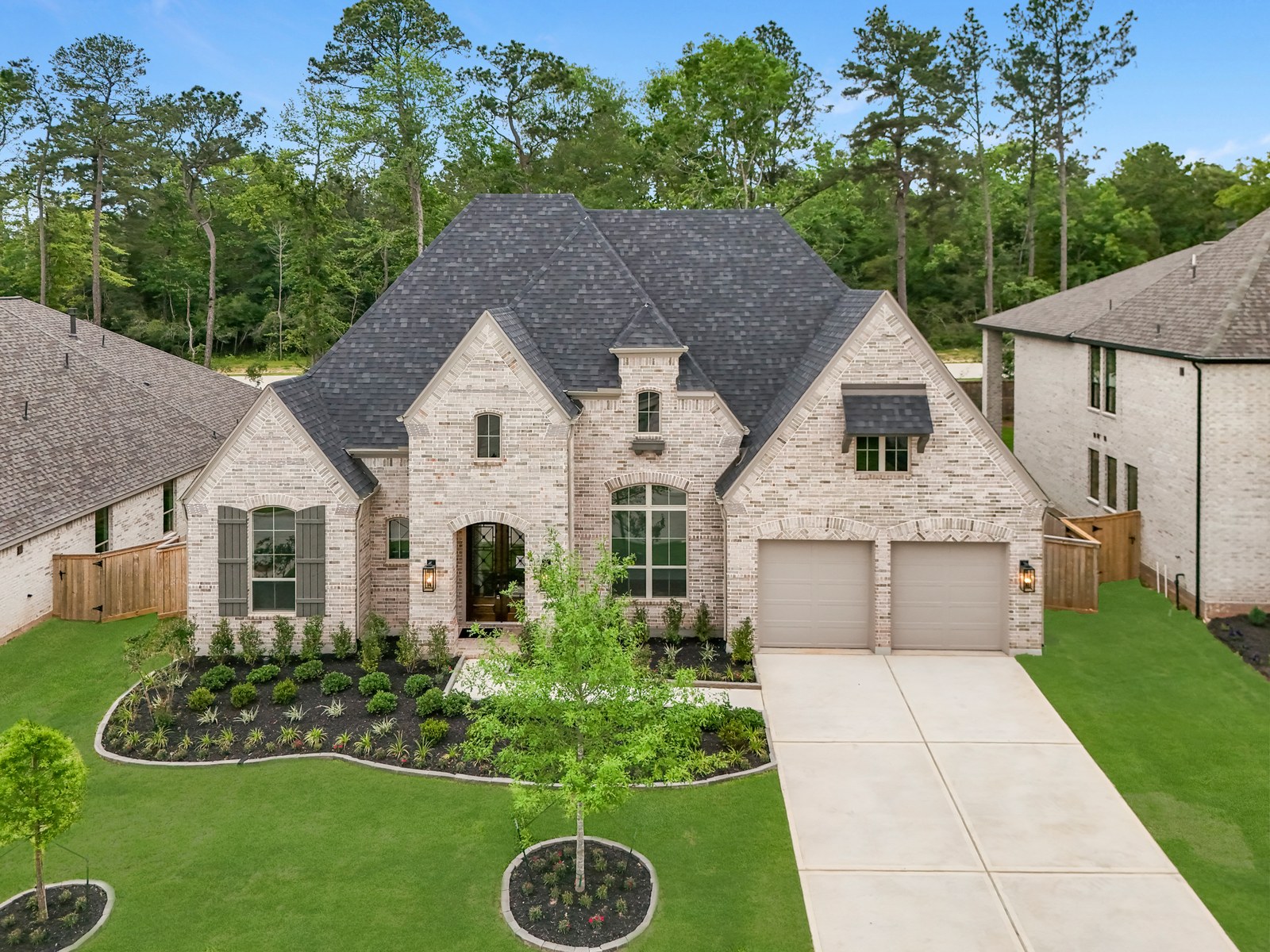 Light brick two-story new-construction home with a two-car garage and fresh landscaping