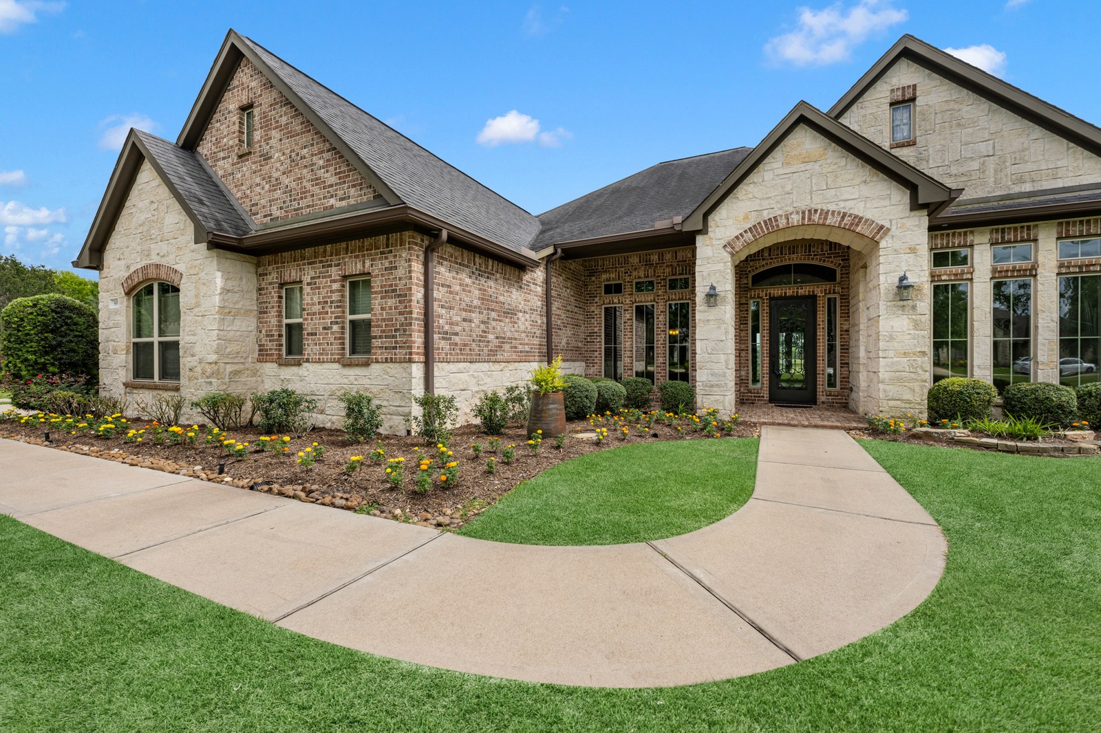 Stone and brick home with a curved front walkway and fresh landscaping