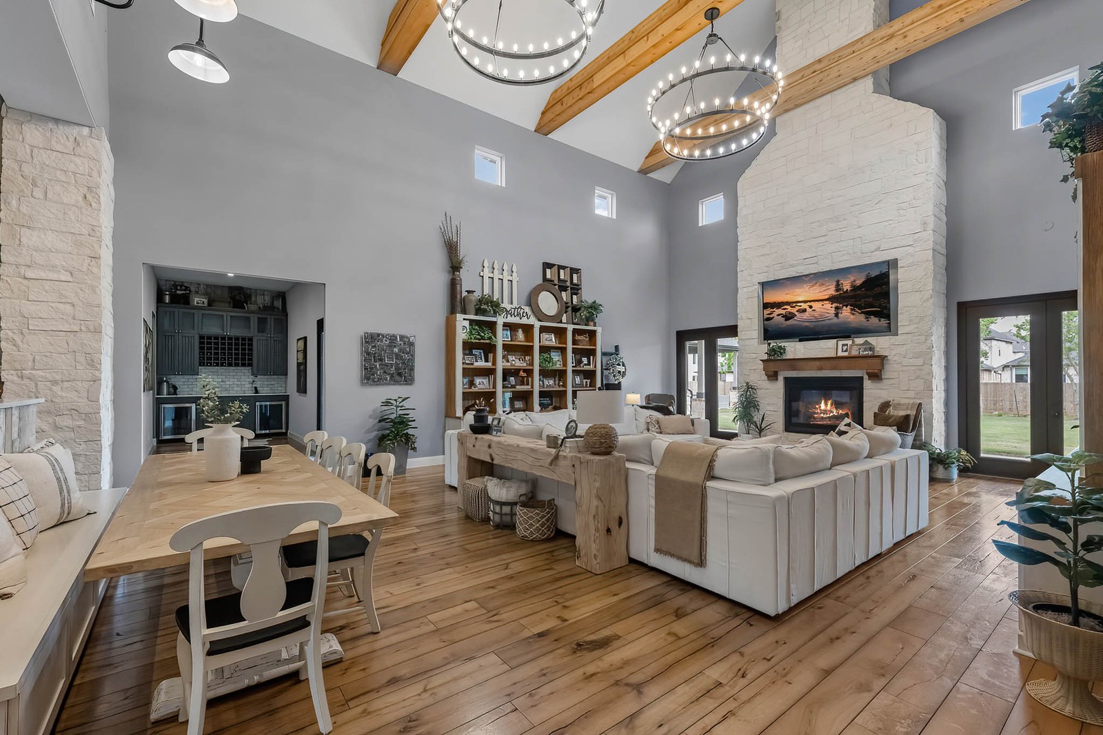 Open great room with beamed vaulted ceiling, stone fireplace and dining table